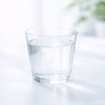 唾液を増やす具体トレーニング|今日からできるドライマウス対策5選 白い背景に置かれた透明なグラスの水。ドライマウス対策や唾液分泌改善をイメージした清潔感のあるビジュアル。